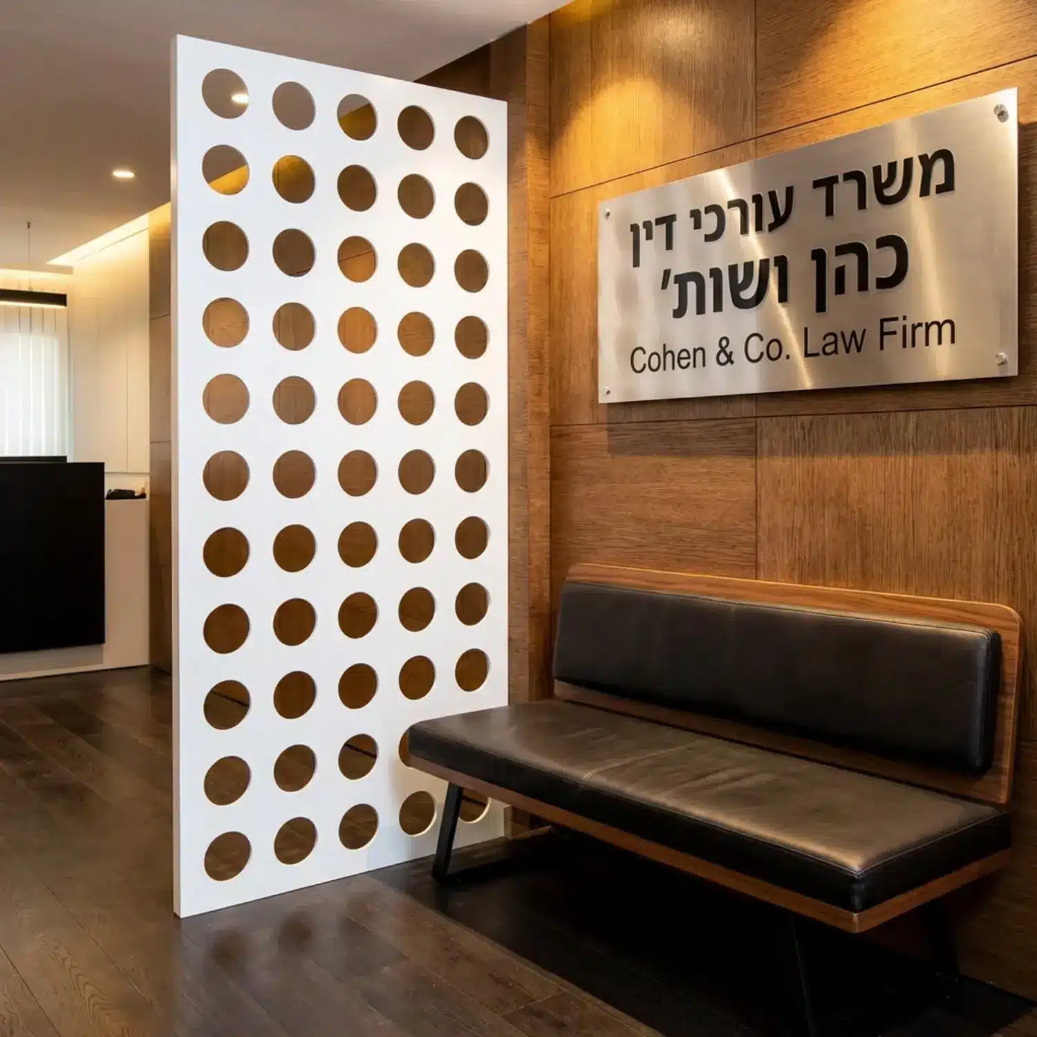 לובי של משרד עורכי דין עם שילוט מתכתי נקי על הקיר וספסל המתנה מעוצב.