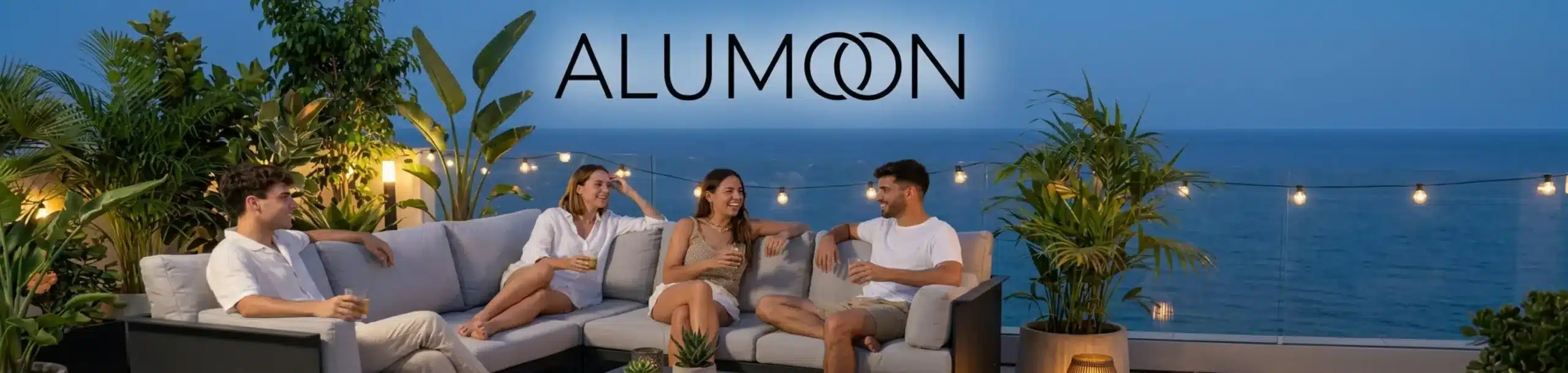 תמונה של חבורת צעירים יושבים ברביצה על מערכת ישיבה מאלומיניום יוקרתי בצבע שחור פחם, עם כריות עבות ומפנקות בגוון אפור בהיר. במרכז שולחן קפה מינימליסטי תואם, באווירת ערב נינוחה במרפסת שמש מודרנית עמוסת עציצים
